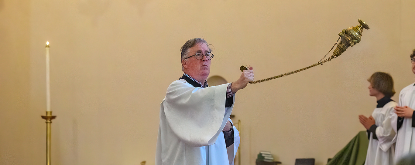 A thurifer censes the congregation with insense. 