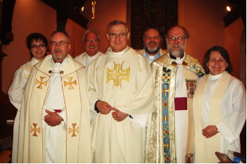 Fr Young in white robes amongst a group of clergy.