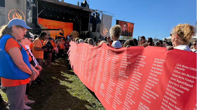 A photo of the memorial cloth being held up by many people. 